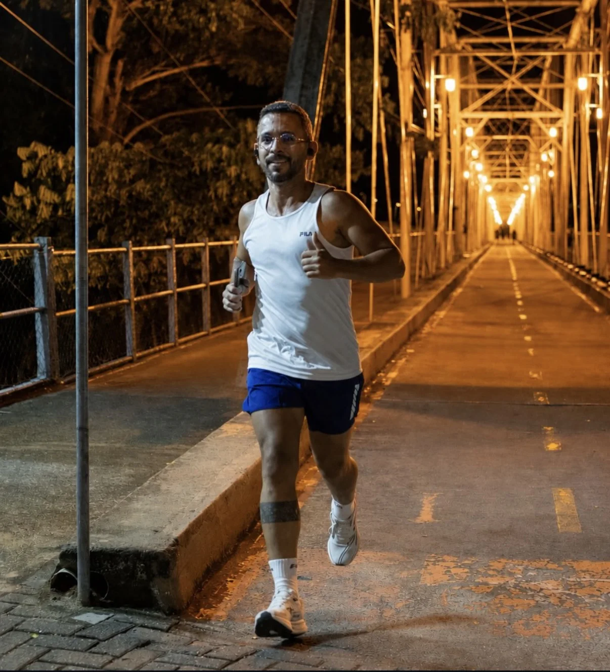 Atleta correndo à noite em uma ponte iluminada