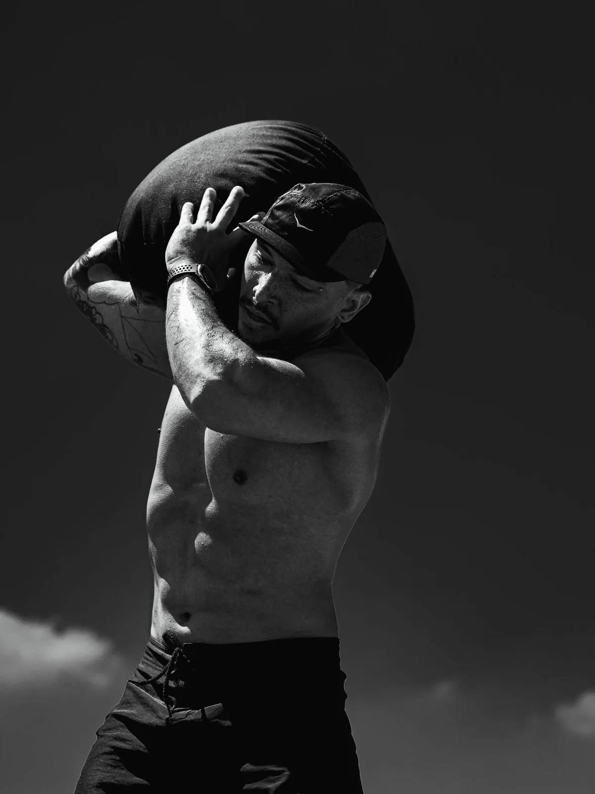 Atleta em treino de força com saco de areia, foto em preto e branco